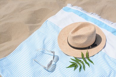 Photo of Beach towel with straw hat, sunglasses and leaves on sand