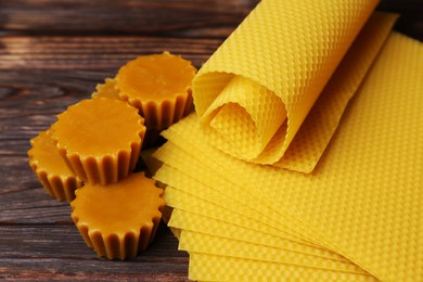 Photo of Natural beeswax cake blocks and sheets on wooden table, closeup
