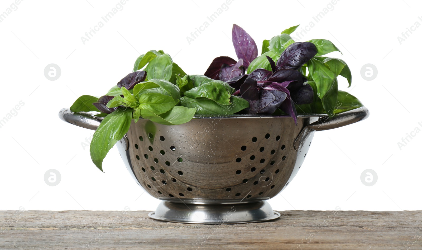 Photo of Metal colander with fresh basil leaves on wooden table against white background