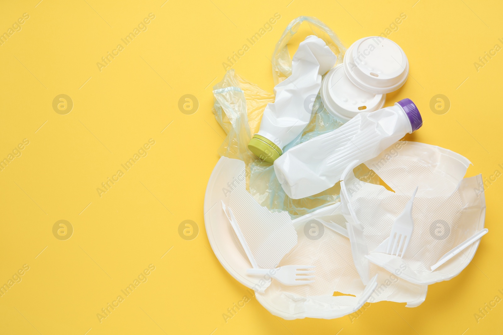 Photo of Pile of different plastic items on yellow background, flat lay. Space for text