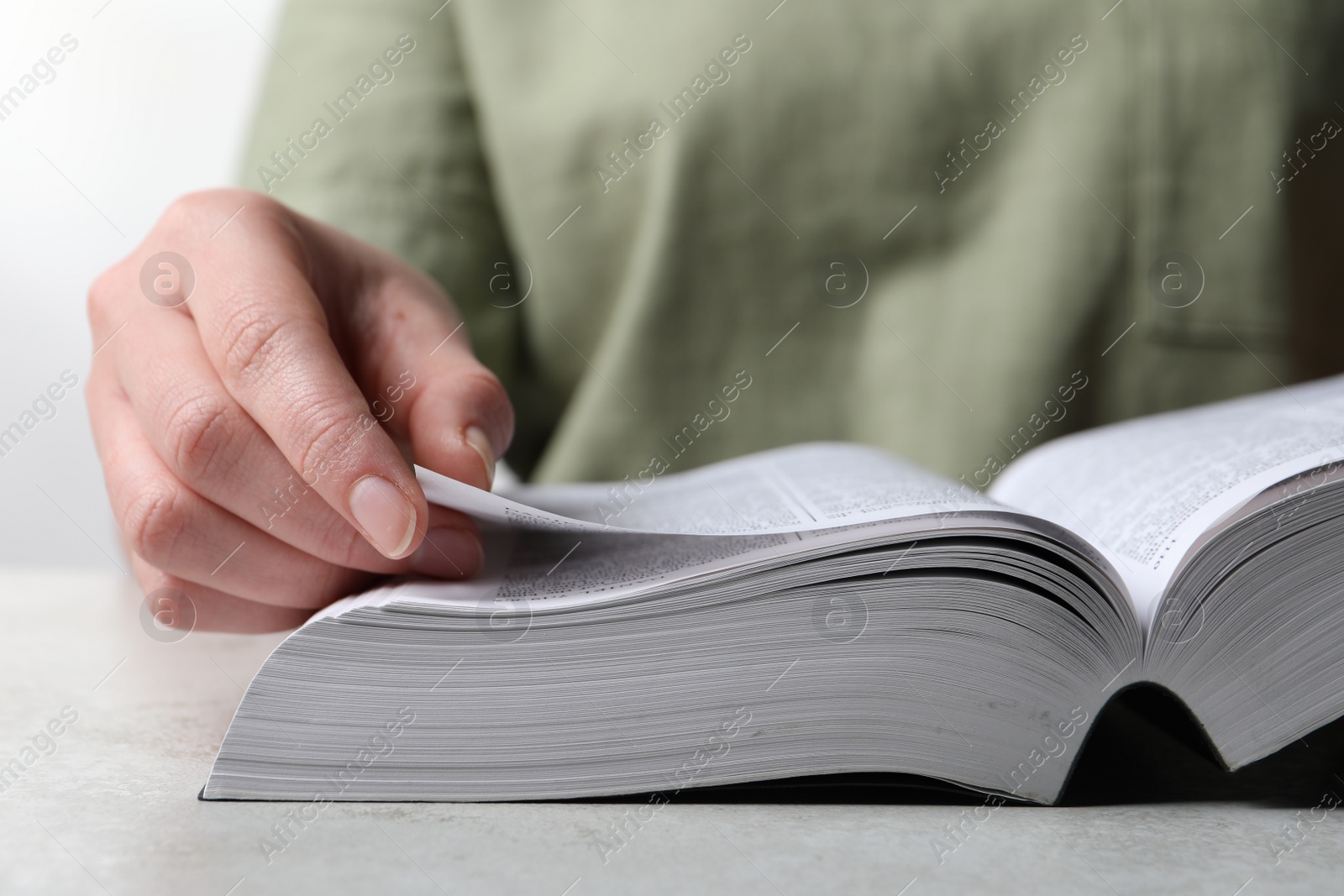 Photo of Woman reading holy Bible at grey textured table, closeup