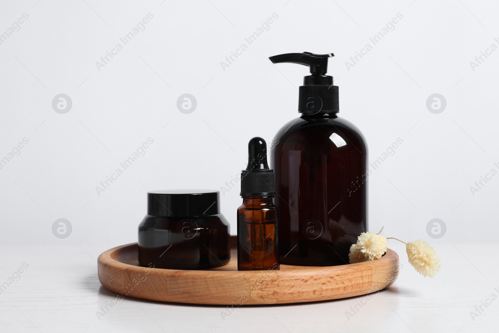 Photo of Different cosmetic products and dry spikes on white wooden table