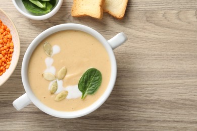 Photo of Healthy cream soup high in vegetable fats, bread and spinach on wooden table, flat lay. Space for text