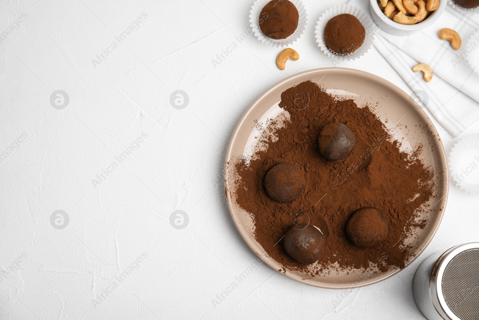 Photo of Delicious chocolate truffles with cocoa powder and nuts on white table, flat lay. Space for text