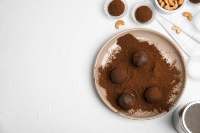 Photo of Delicious chocolate truffles with cocoa powder and nuts on white table, flat lay. Space for text