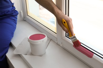 Image of Man painting window frame at home, closeup