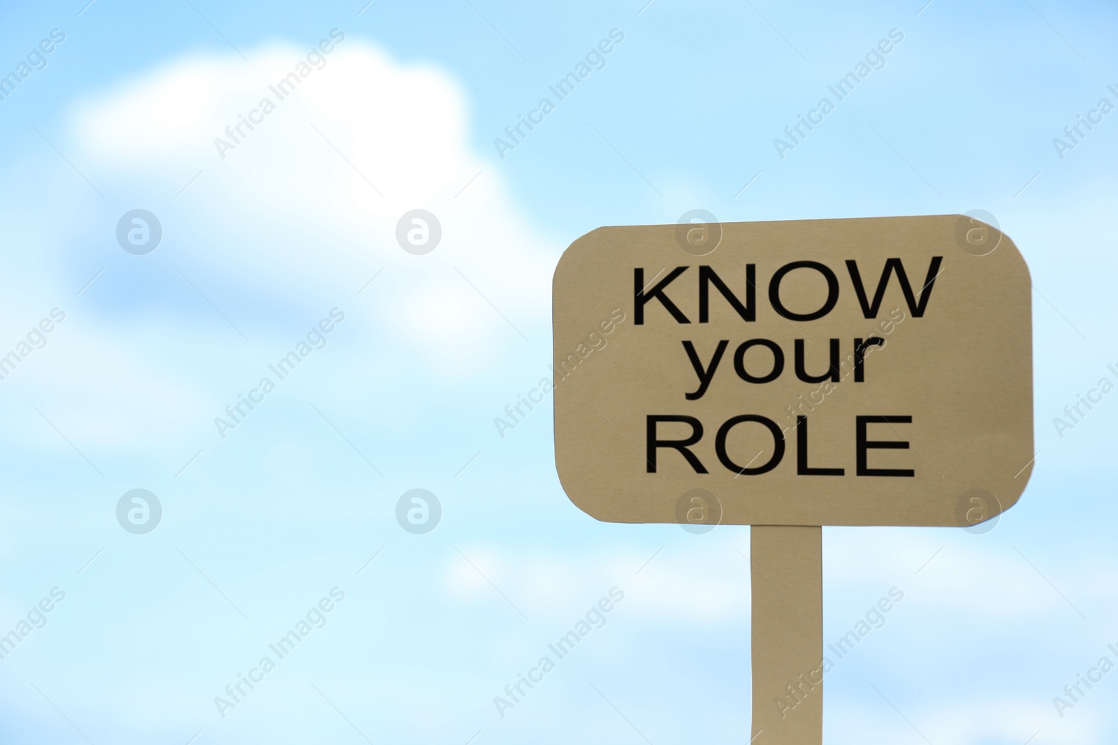Photo of Cardboard sign with phrase Know Your Role against cloudy sky, space for text