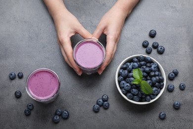 Photo of Woman with tasty blueberry smoothie at grey table, top view