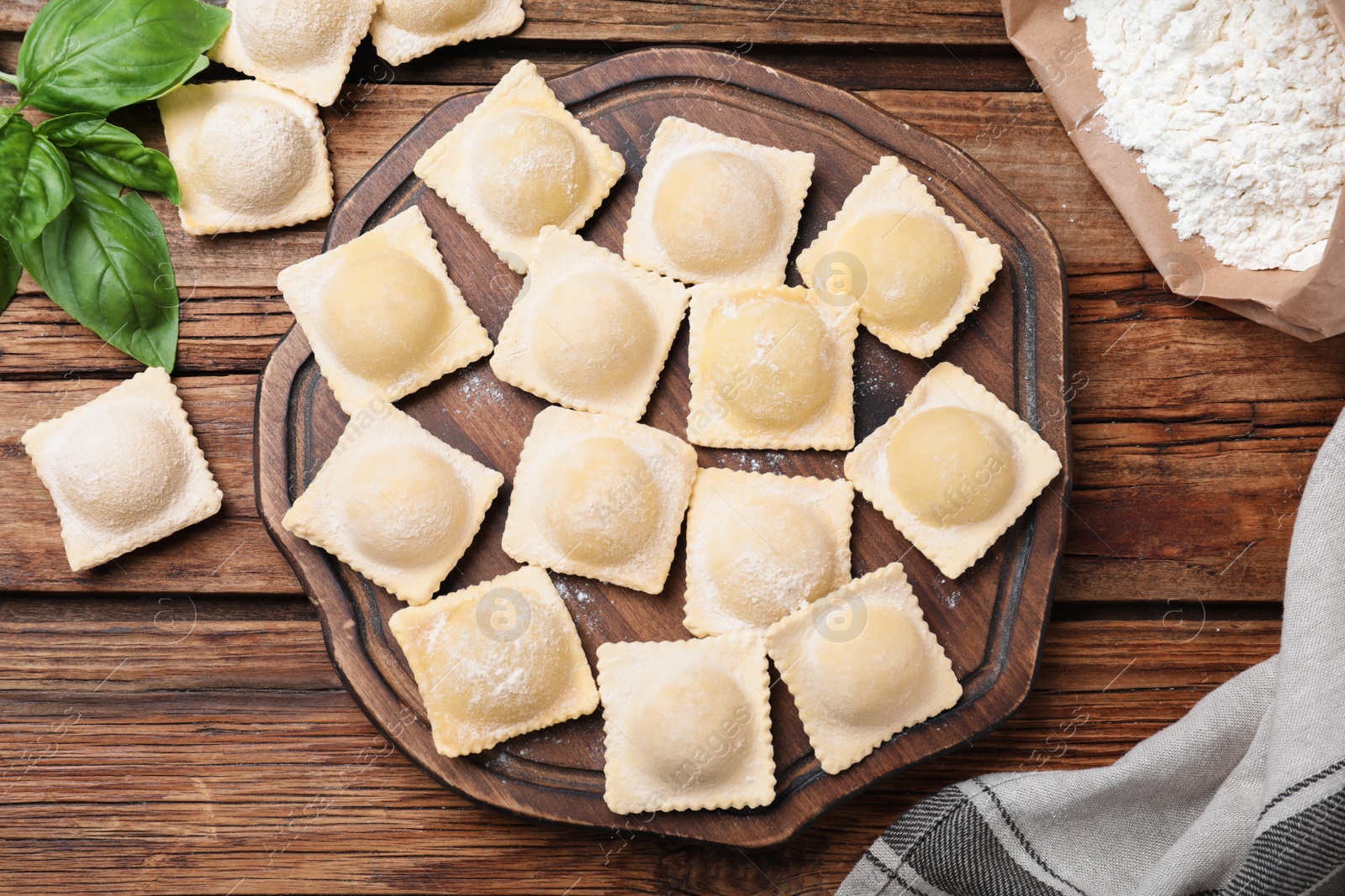 Photo of Homemade uncooked ravioli on wooden table, flat lay