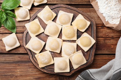 Photo of Homemade uncooked ravioli on wooden table, flat lay