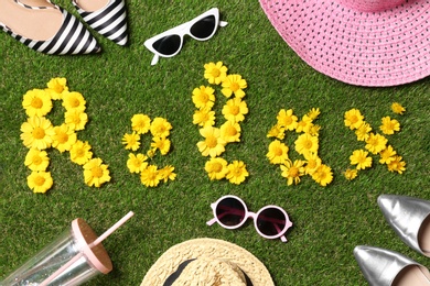 Photo of Flat lay composition with word RELAX of yellow flowers on green grass