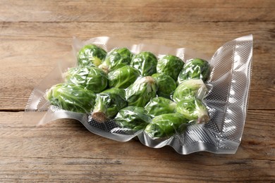 Photo of Vacuum pack of Brussels sprouts on wooden table