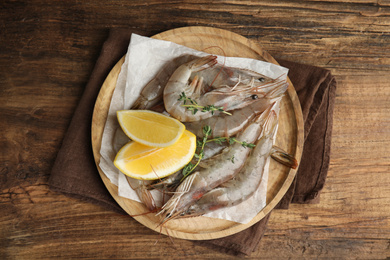 Photo of Fresh raw shrimps with lemon slices on wooden table, top view