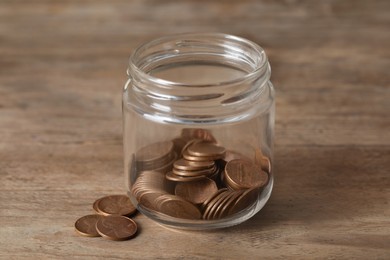 Glass jar with coins on wooden table