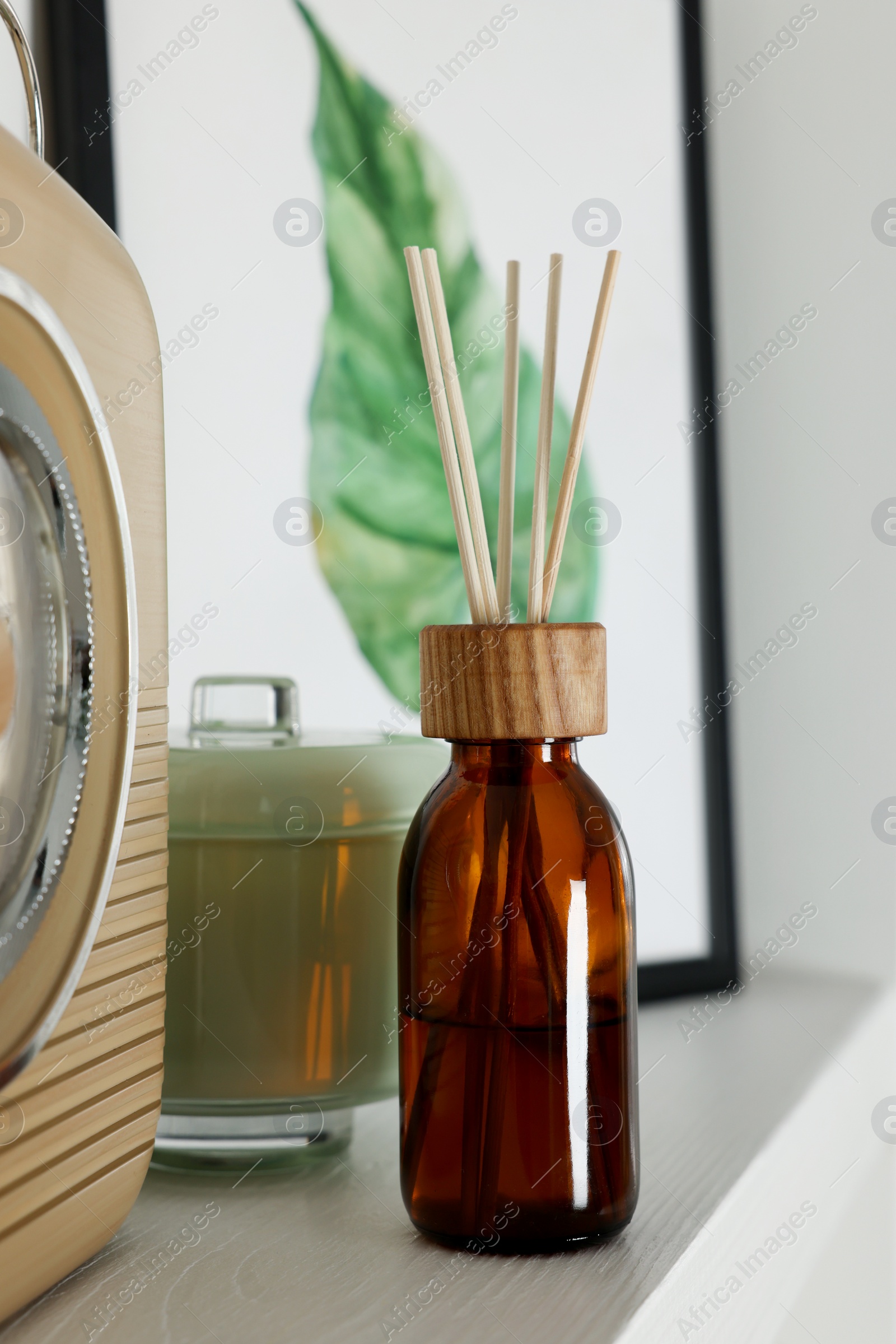 Photo of Aromatic reed air freshener and decor on white wooden shelf indoors
