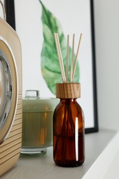 Aromatic reed air freshener and decor on white wooden shelf indoors