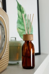 Photo of Aromatic reed air freshener and decor on white wooden shelf indoors