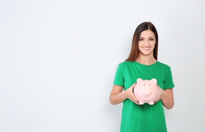 Photo of Young woman with piggy bank on white background. Space for text