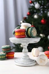 Photo of Different decorated Christmas macarons on white table indoors