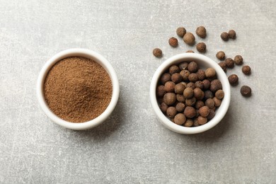 Ground allspice pepper and grains in bowls on grey table, top view