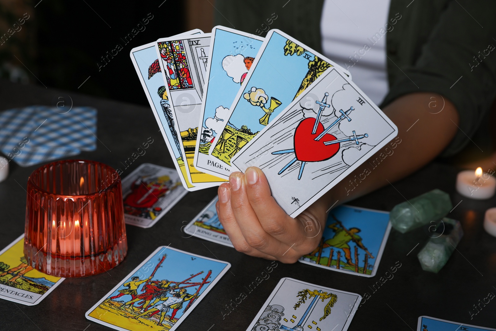 Photo of Fortune teller with tarot cards at grey table indoors, closeup