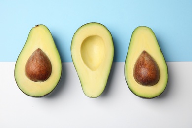 Cut fresh ripe avocados on color background, flat lay