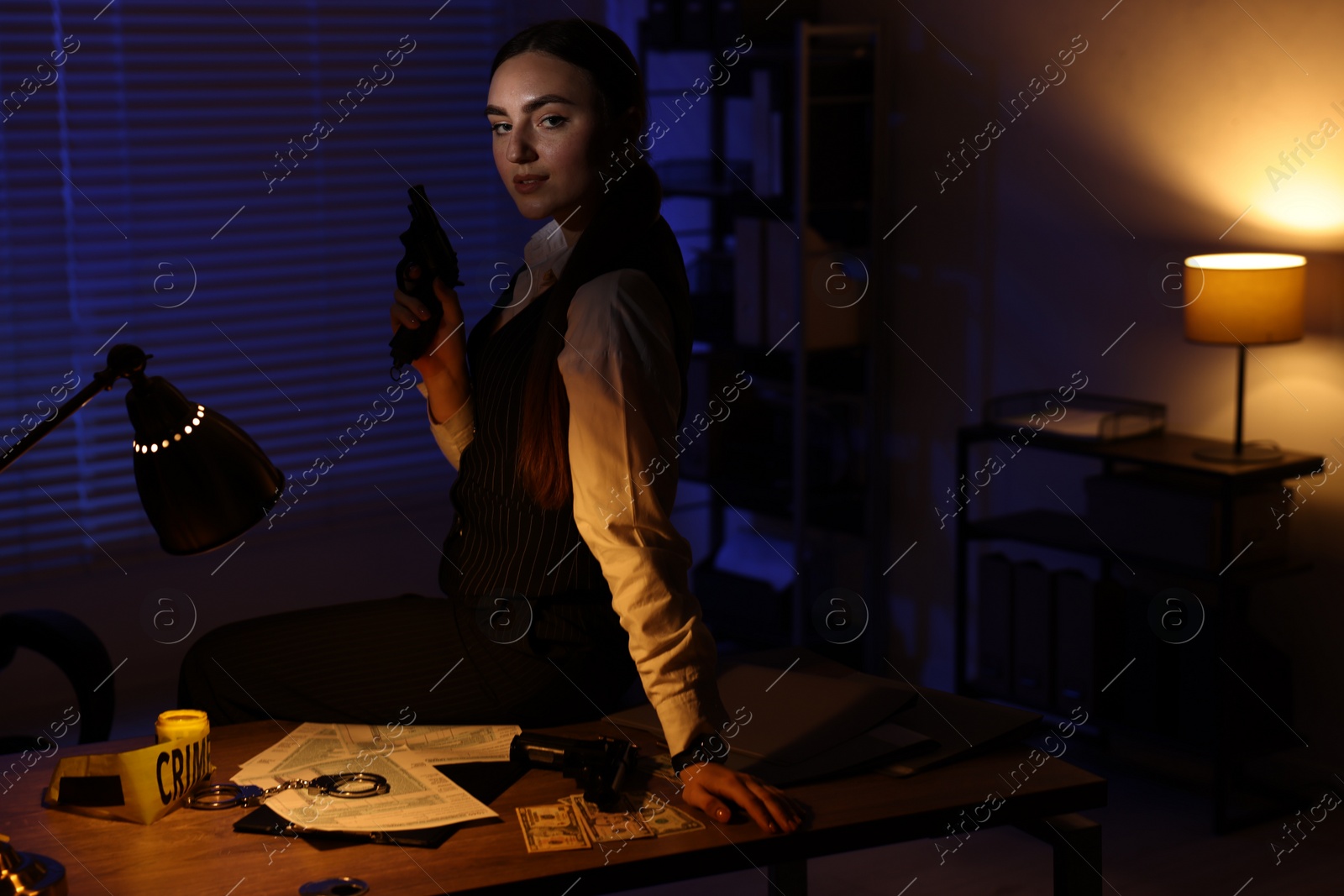 Photo of Professional detective with handgun in office at night. Space for text