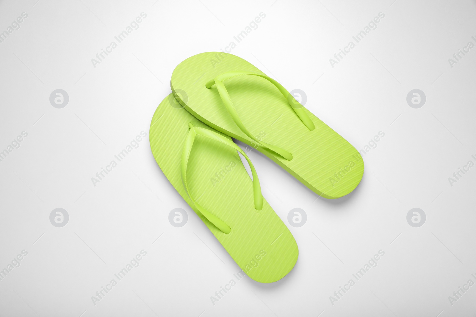 Photo of Light green flip flops on white background, top view