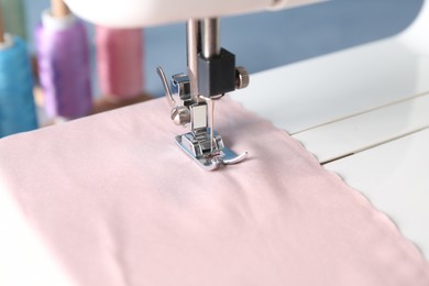 White sewing machine with color fabric on light background, closeup