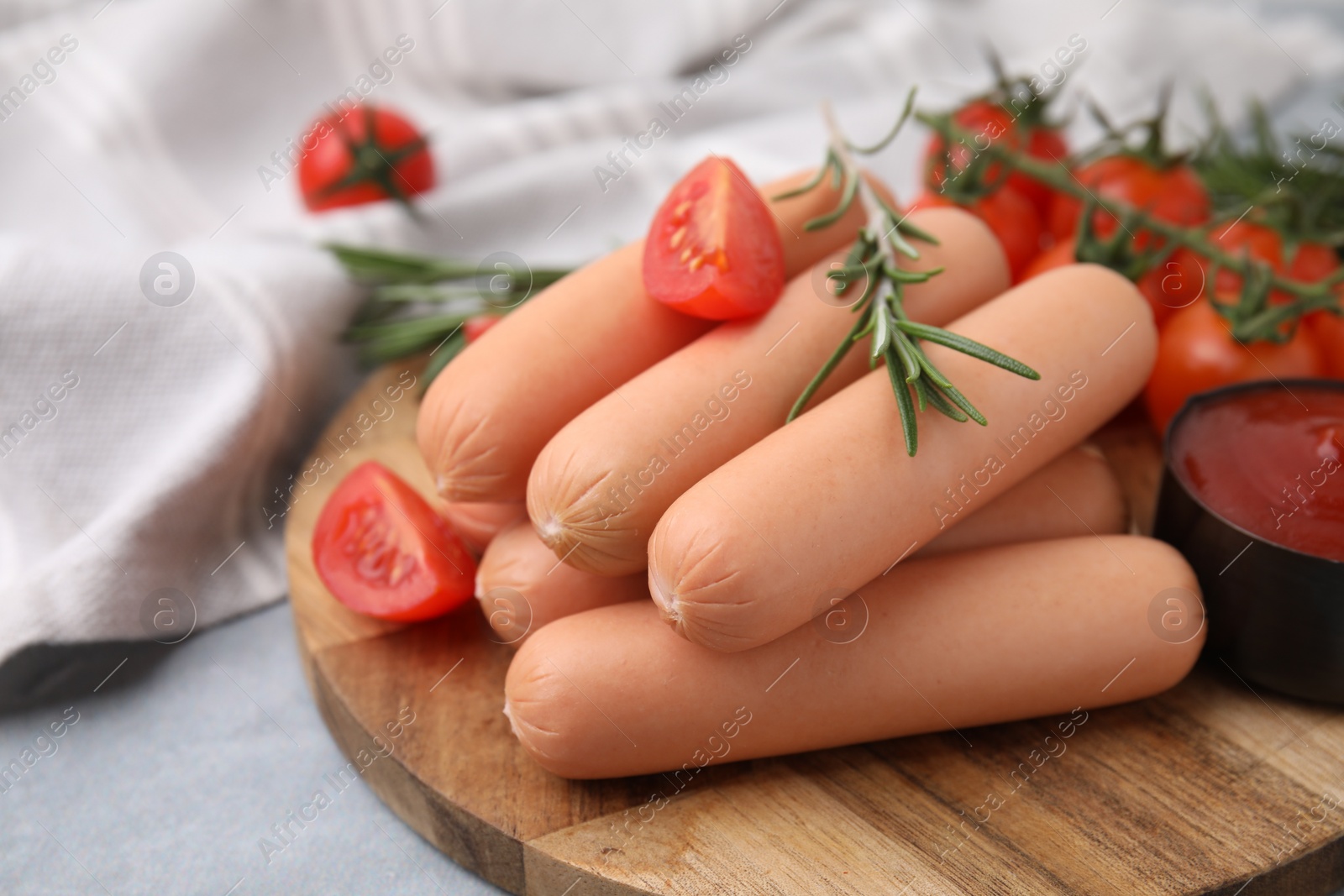 Photo of Delicious boiled sausages, tomatoes and rosemary on gray table, closeup