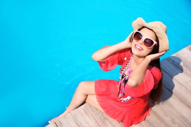 Beautiful young woman sitting near swimming pool