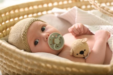 Photo of Cute newborn baby on white blanket in wicker crib, closeup