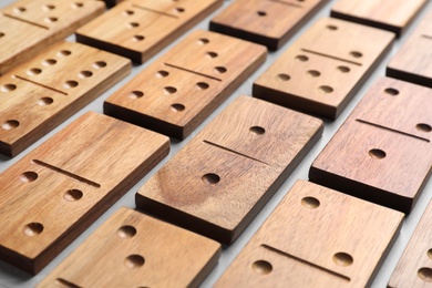 Photo of Set of wooden domino tiles on grey table, closeup