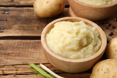 Photo of Bowls of tasty mashed potato, pepper and leeks on wooden table, space for text