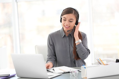 Young woman talking on phone through headset at workplace