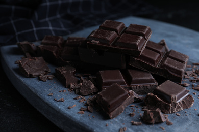 Photo of Pieces of delicious dark chocolate on grey board
