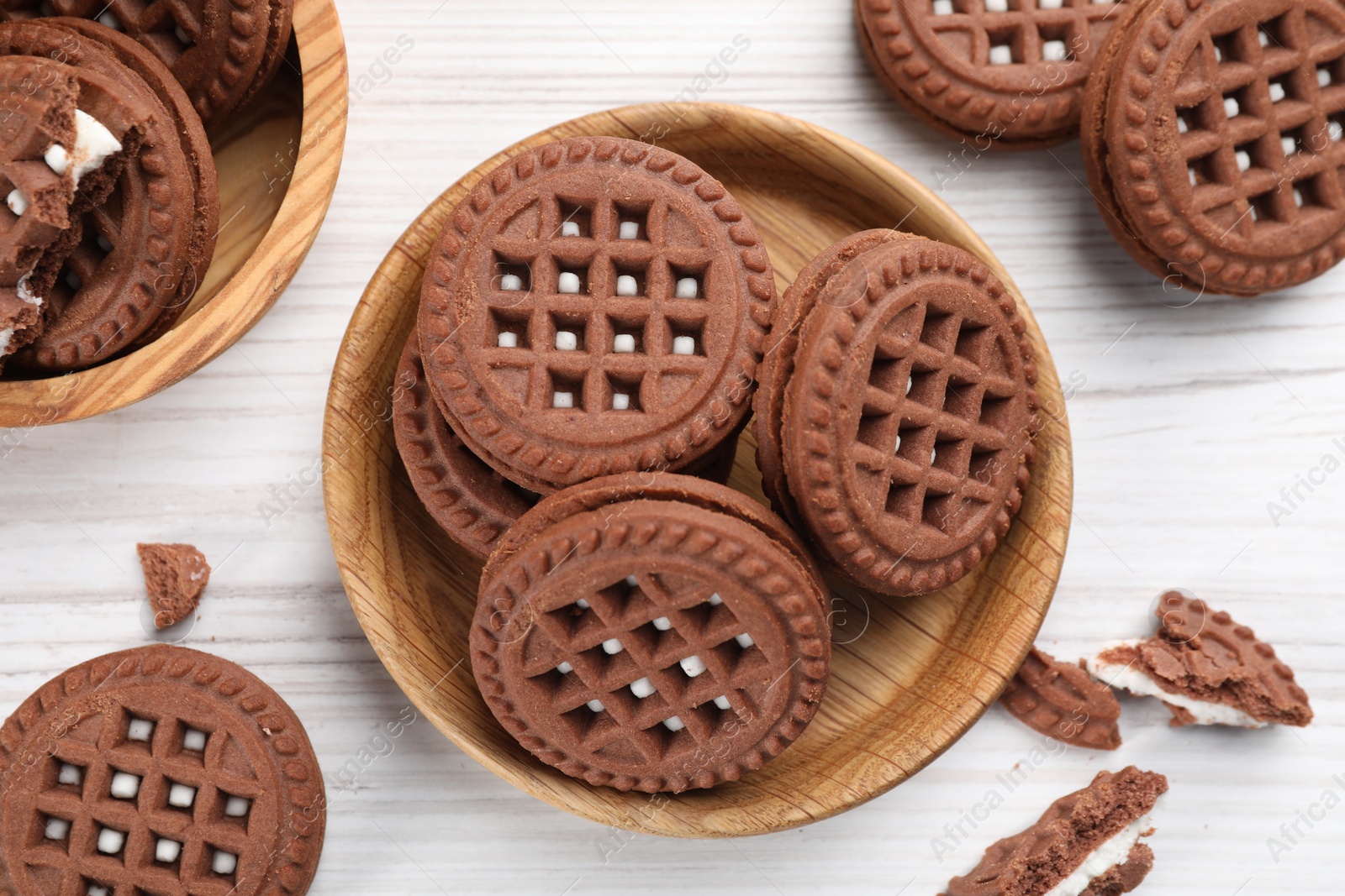 Photo of Tasty chocolate sandwich cookies with cream on white wooden table, flat lay