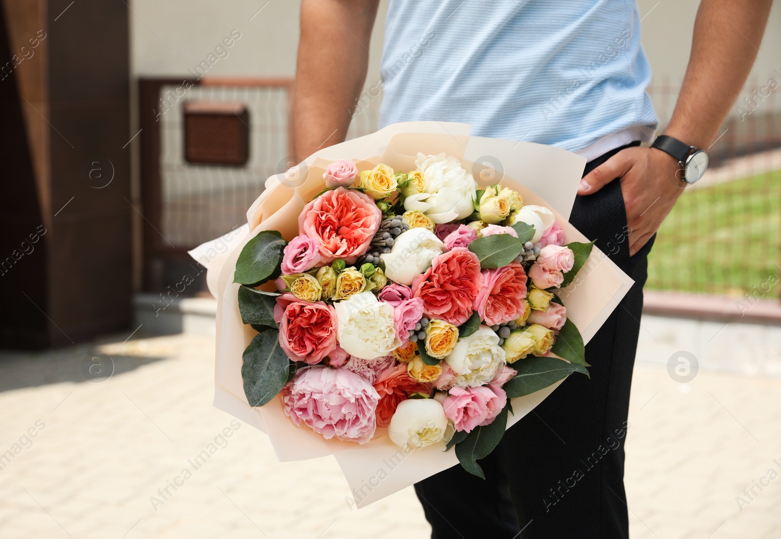 Photo of Young man with beautiful flower bouquet outdoors, closeup view. Space for text