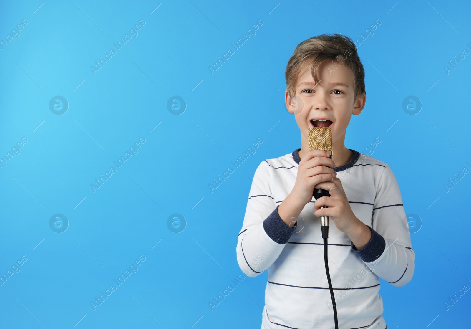 Photo of Cute boy singing in microphone on color background. Space for text