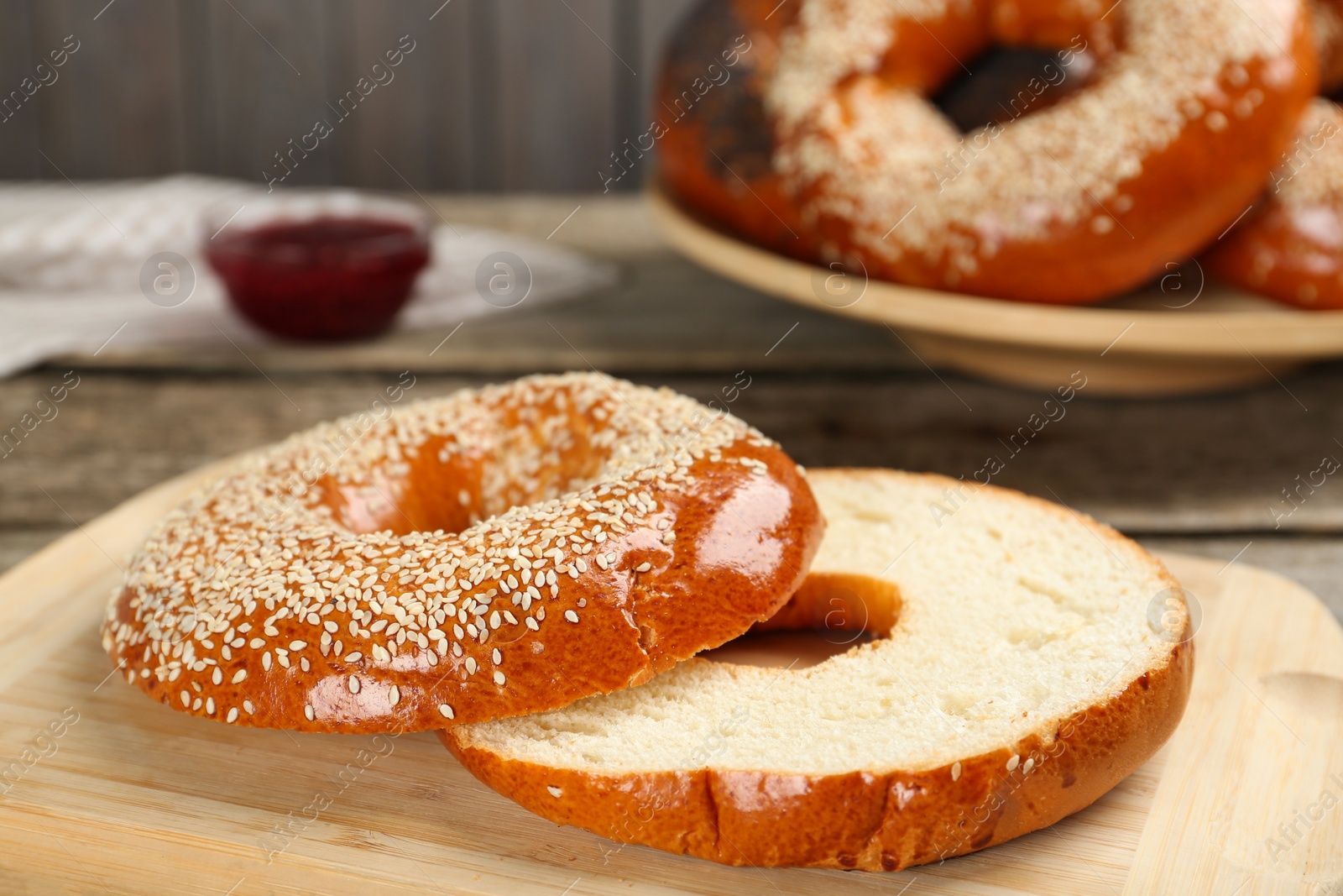 Photo of Delicious fresh halved bagel on wooden board, closeup