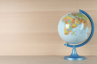 Plastic model globe of Earth on wooden table, space for text. Geography lesson