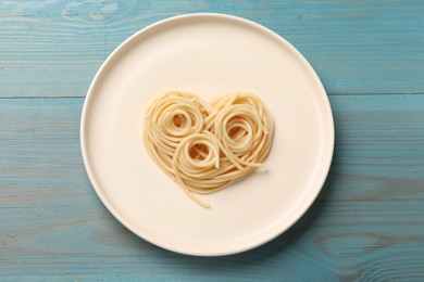 Photo of Heart made of tasty spaghetti on light blue wooden table, top view