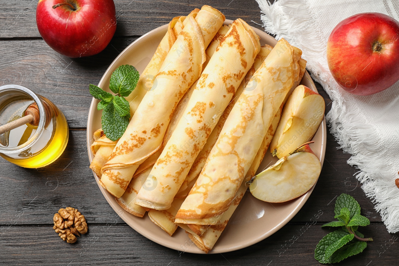 Photo of Delicious thin pancakes on wooden table, flat lay