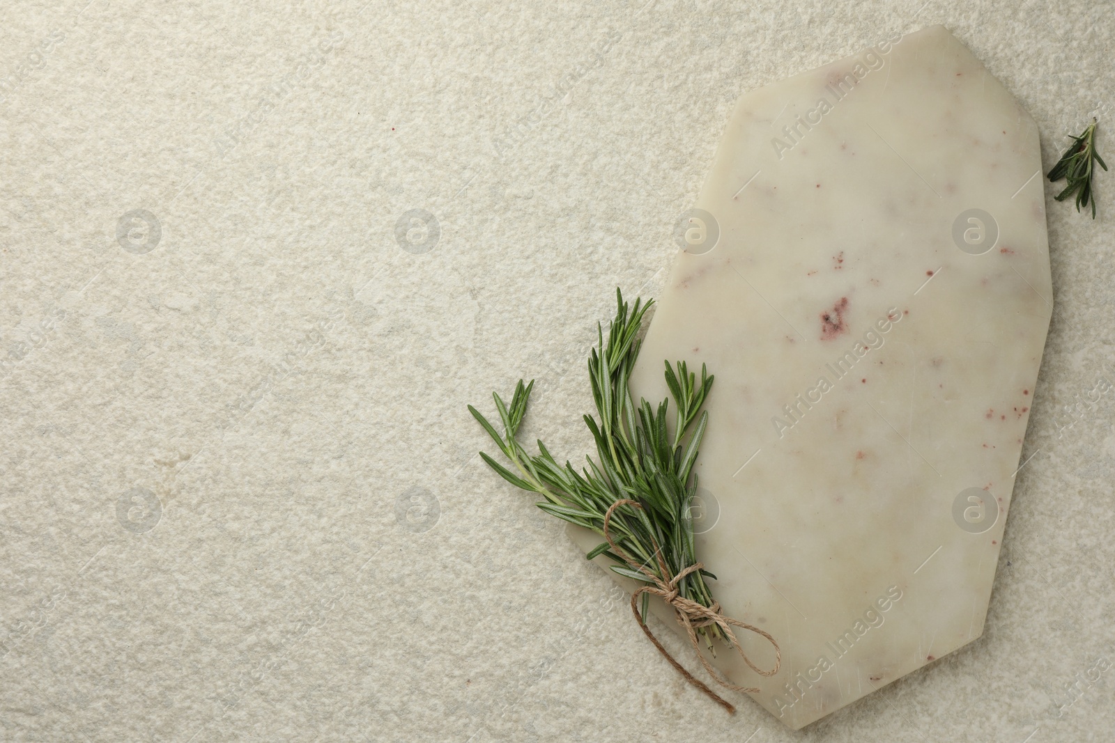 Photo of Cutting board and rosemary on white textured table, flat lay. Space for text