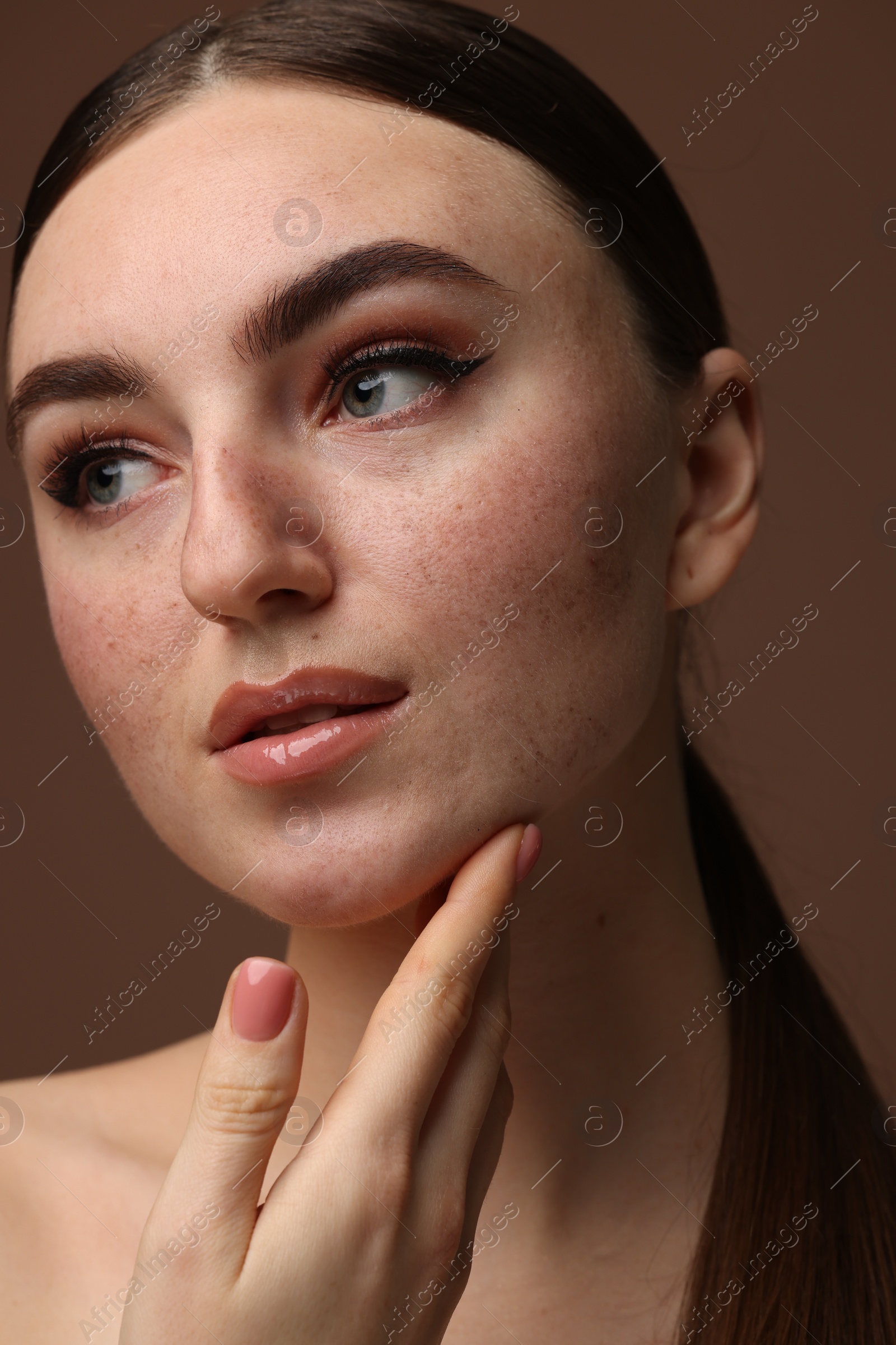 Photo of Portrait of beautiful woman with fake freckles on brown background, closeup