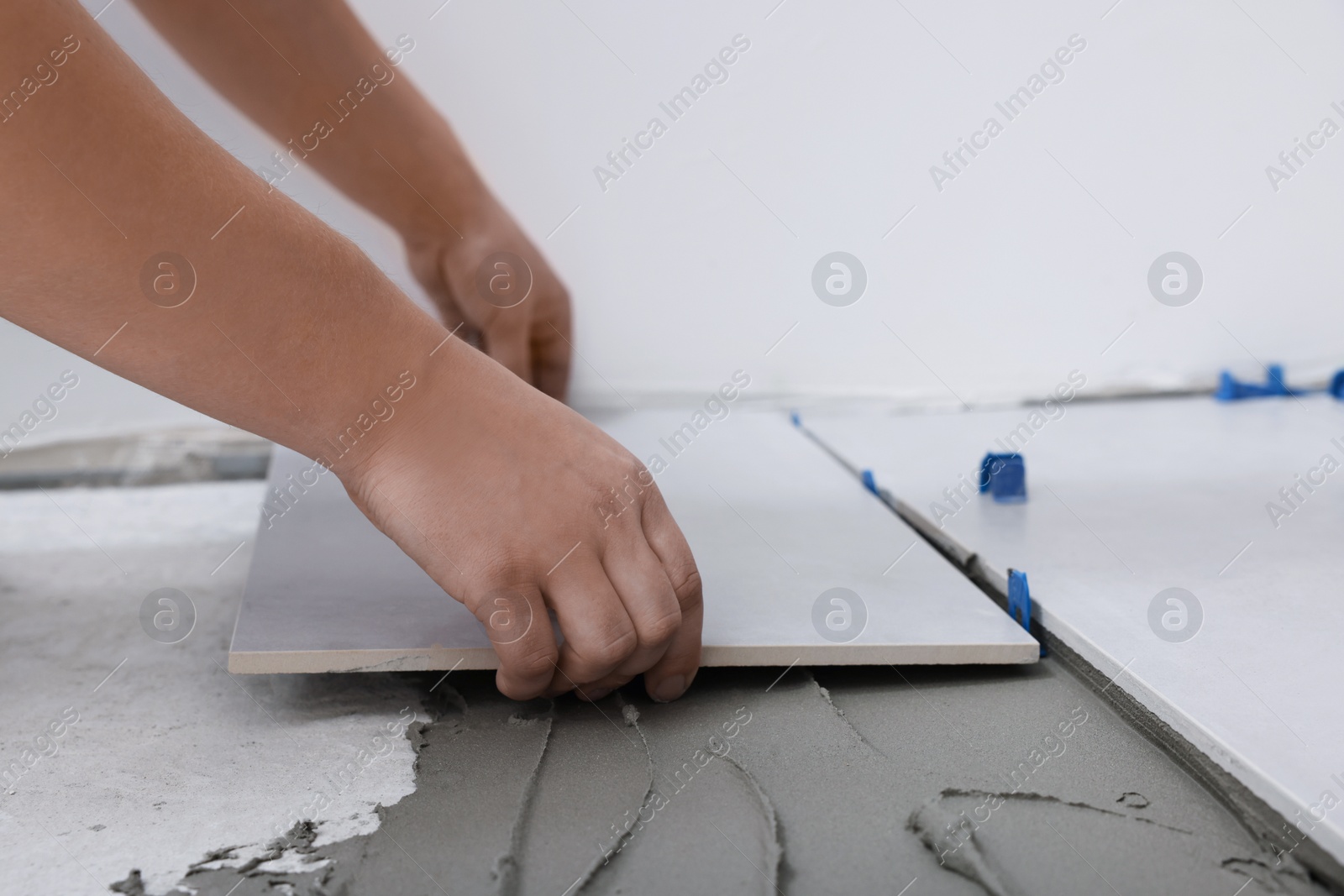 Photo of Worker installing ceramic tile on floor, closeup