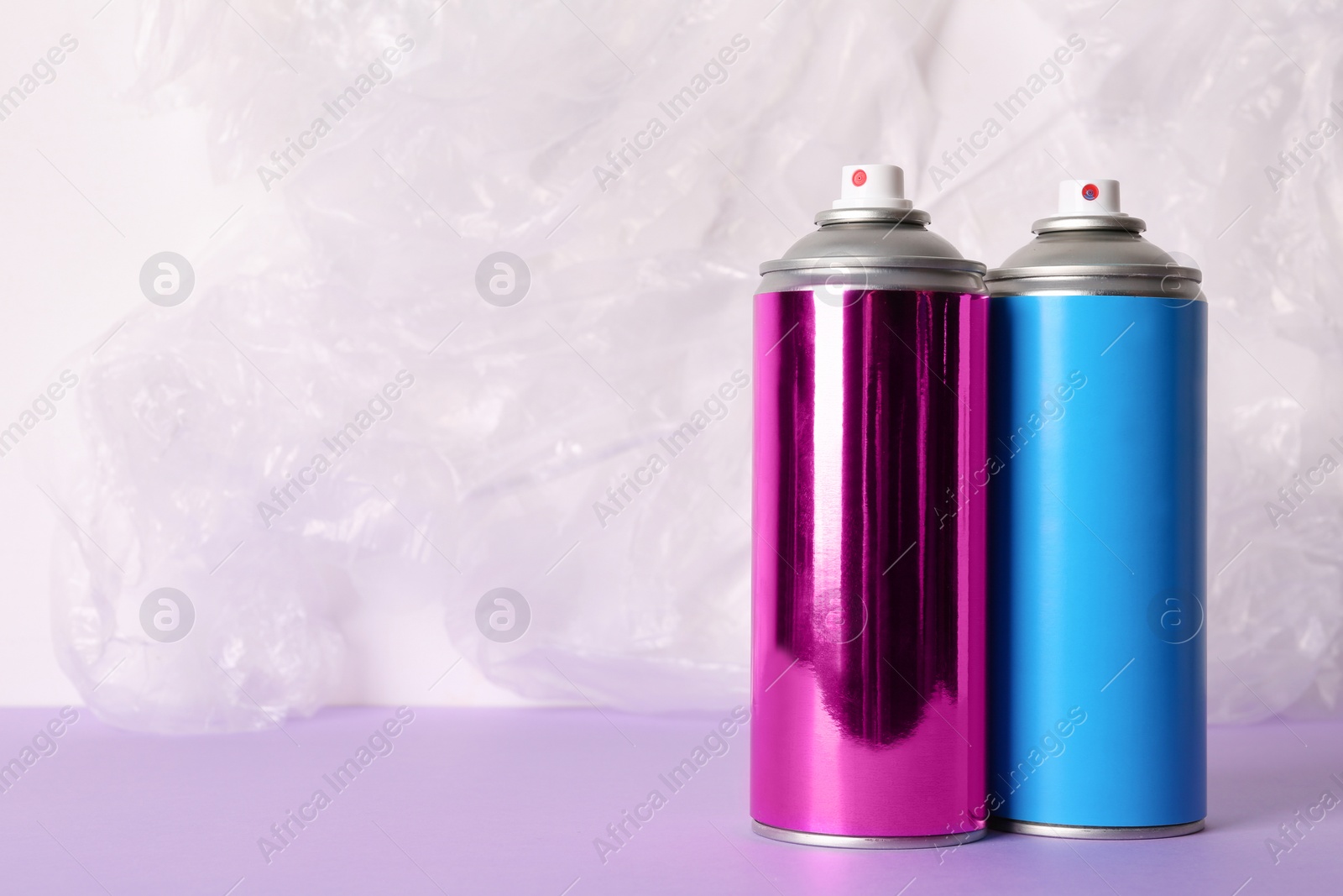 Photo of Cans of different spray paints on color background. Space for text