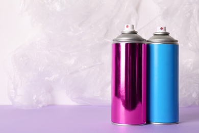 Photo of Cans of different spray paints on color background. Space for text