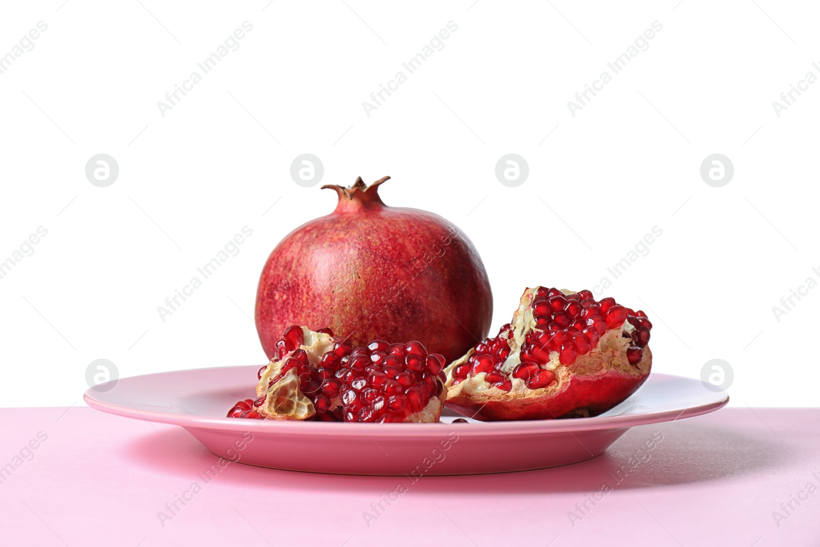 Photo of Plate with ripe pomegranates on table against white background