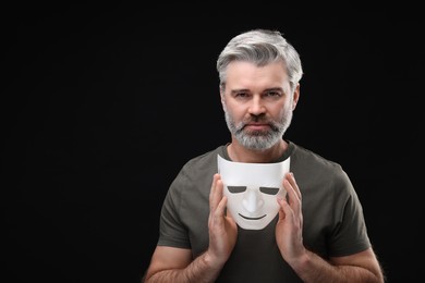 Photo of Multiple personality concept. Man with mask on black background. Space for text